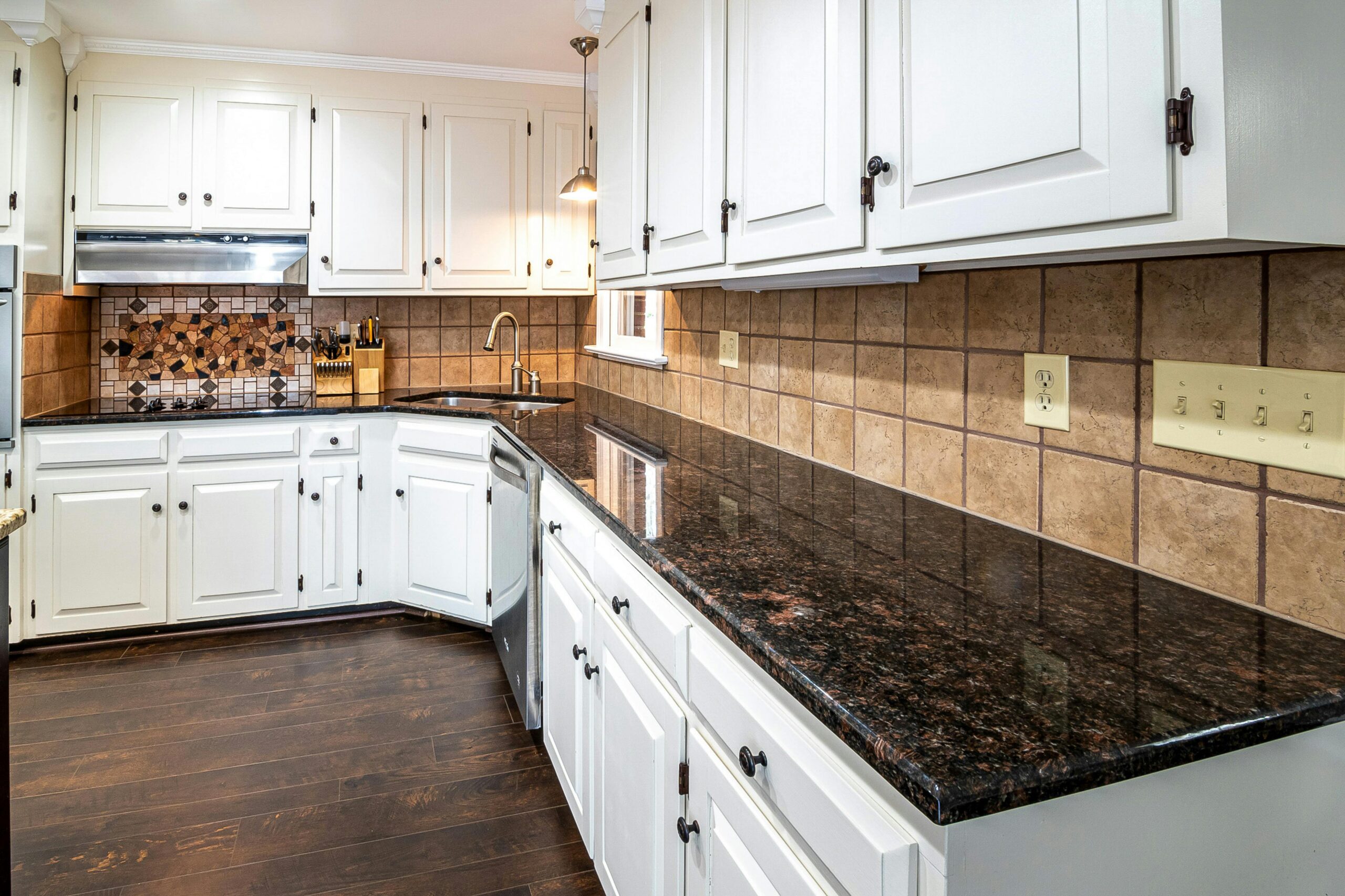 Stylish kitchen featuring granite countertops, white cabinets, and a tiled backsplash, perfect for a contemporary home.
